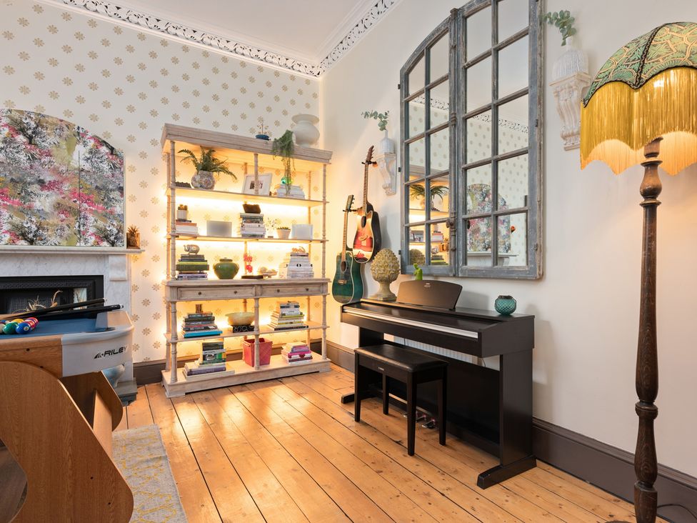 A living room with a piano and a bookshelf at The Old Barn in Manchester