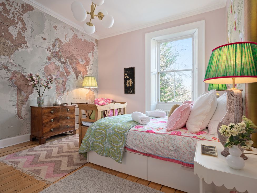 A bedroom with a world map wall and wooden furniture at The Old Barn in Manchester