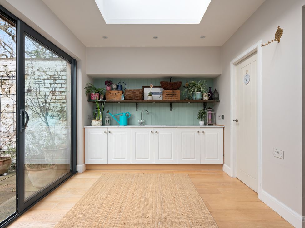 A kitchen with a sink and shelves filled with plants at The Old Barn in Manchester