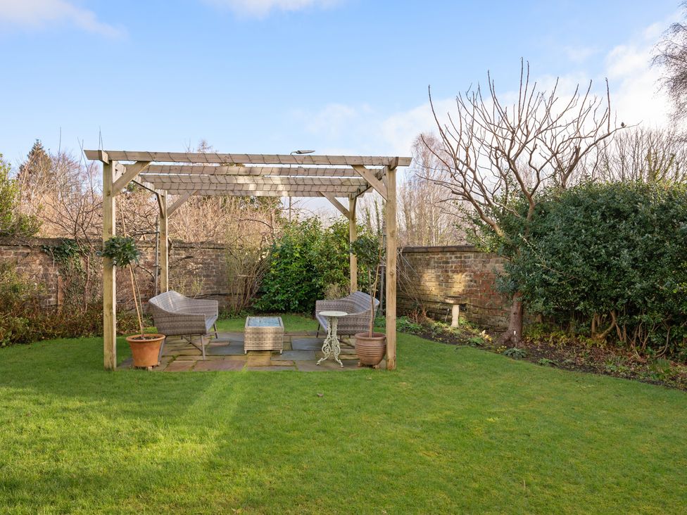 A garden with a pergola, chairs, and a table at the property