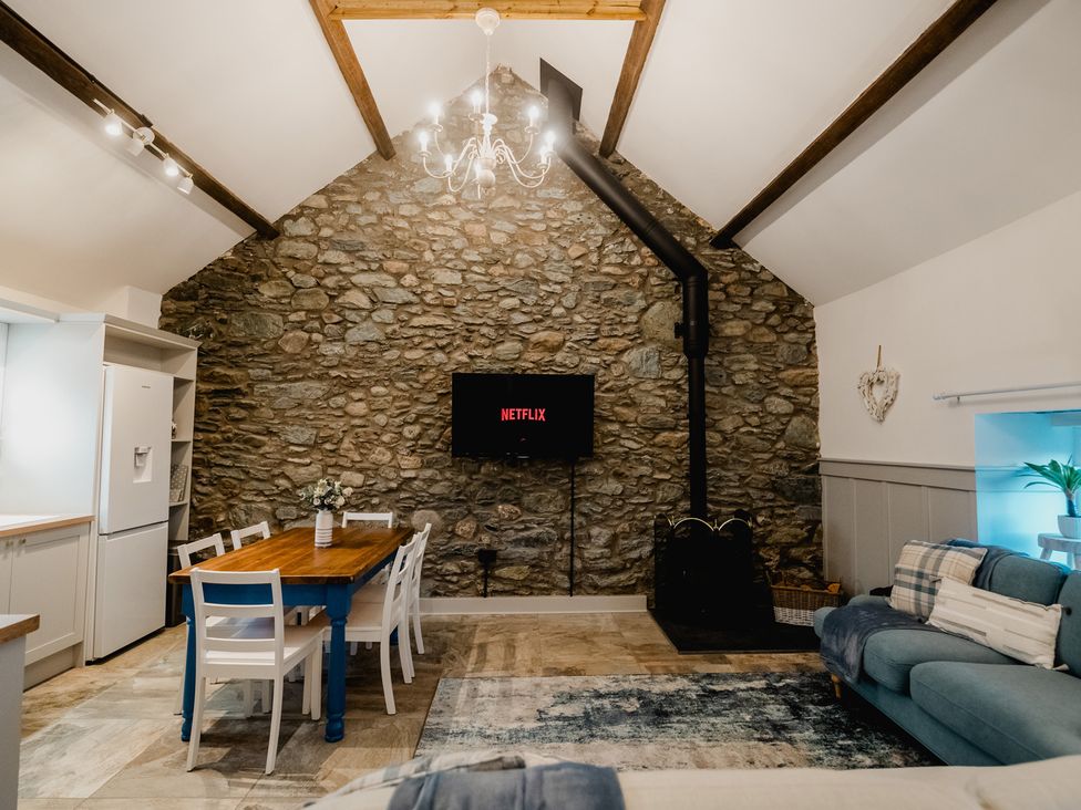 A living room with a dining table and television at The Old Barn in Manchester