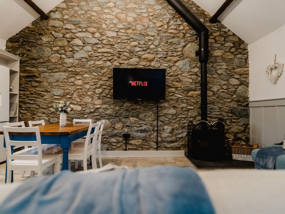 A living room with a dining table and television at The Old Barn in Manchester