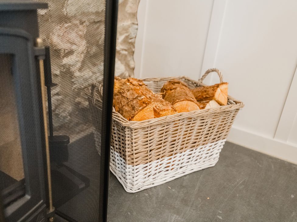 A log basket with firewood next to a fireplace in a living room