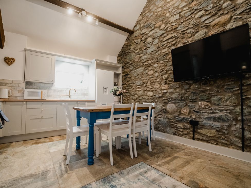 A kitchen with a stone wall and dining table at The Old Barn in Manchester