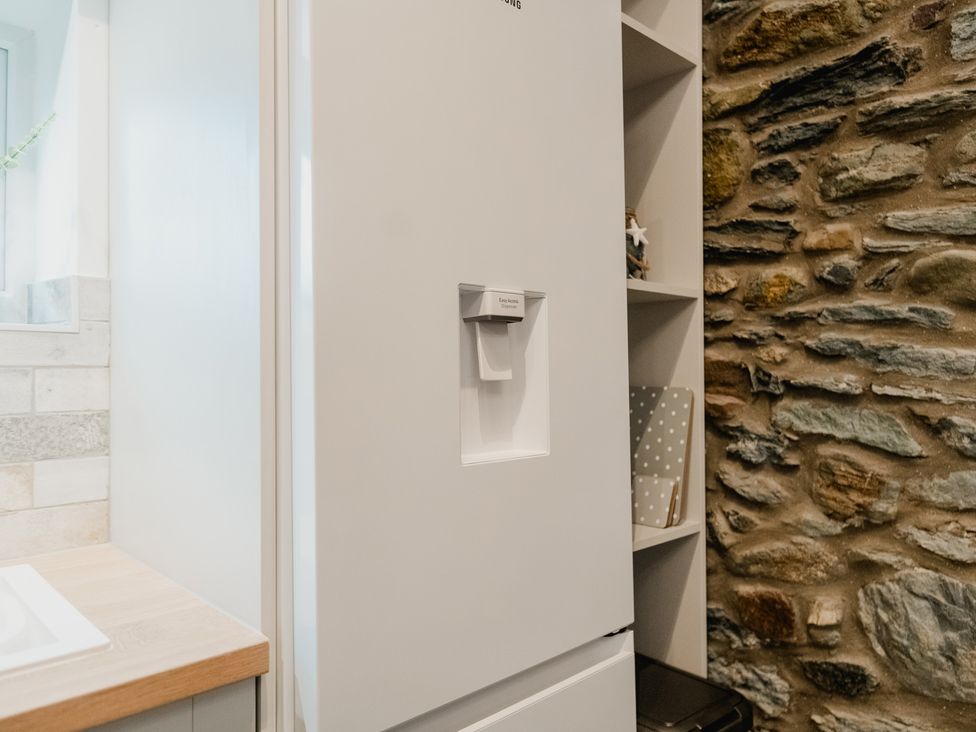 A kitchen with a refrigerator and stone wall features at The Old Barn in Manchester