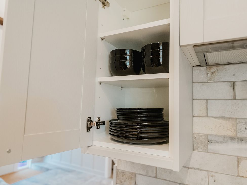 A cabinet with black plates and bowls at the kitchen