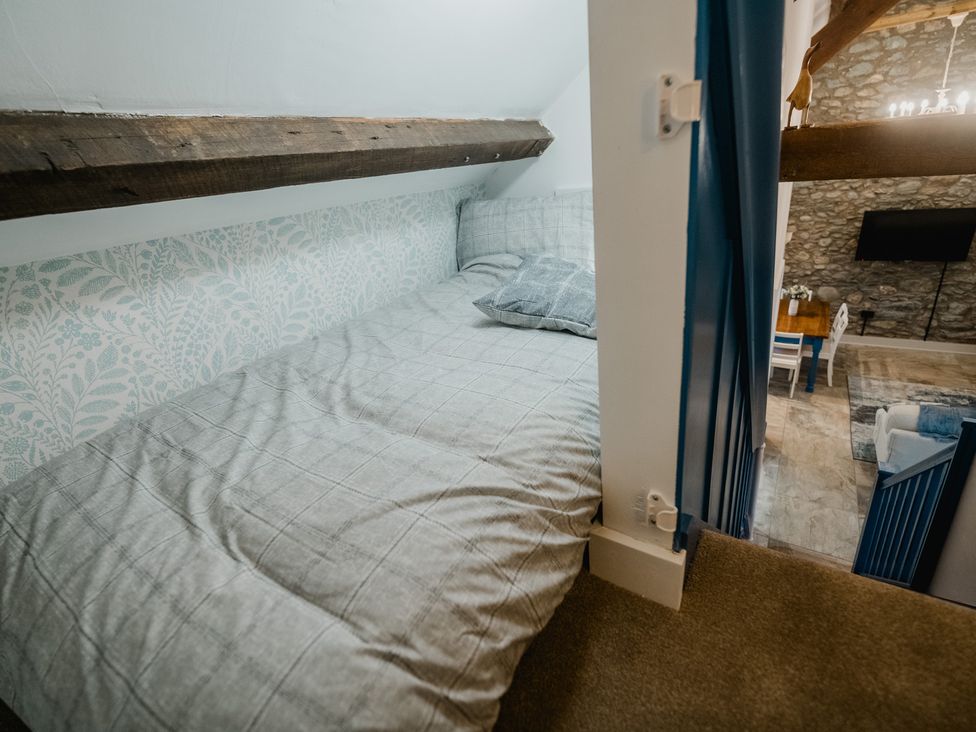 A loft bedroom with a bed and patterned wall at The Old Barn in Manchester