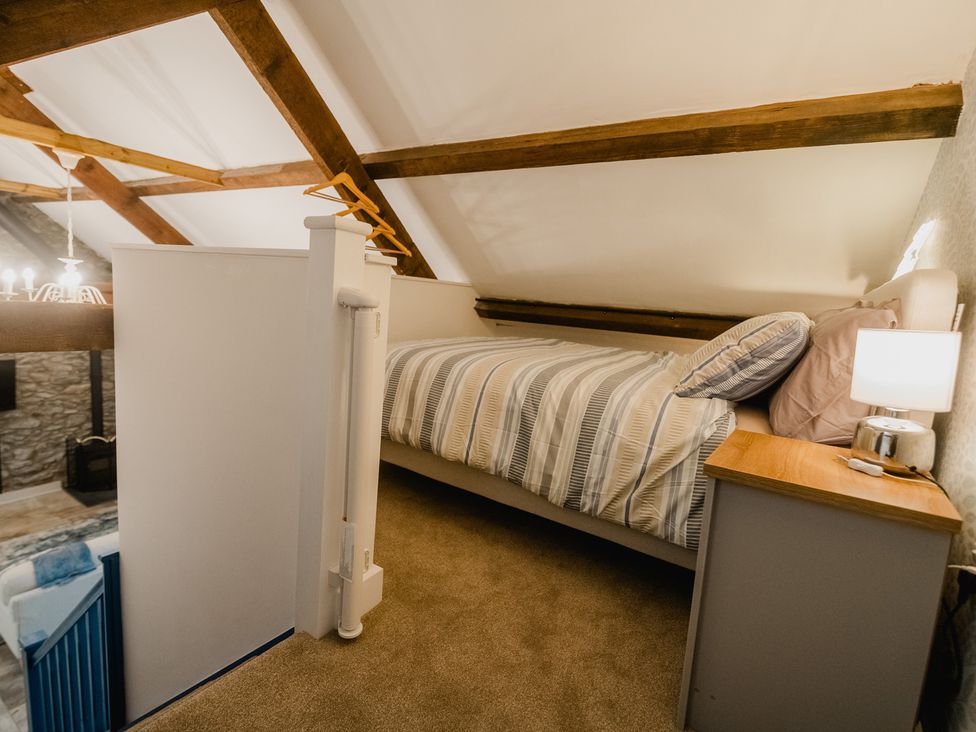 A loft bedroom with a bed and bedside table at The Old Barn in Manchester