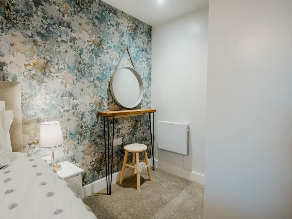 A bedroom with a bed and a mirror on a table at The Old Barn in Manchester