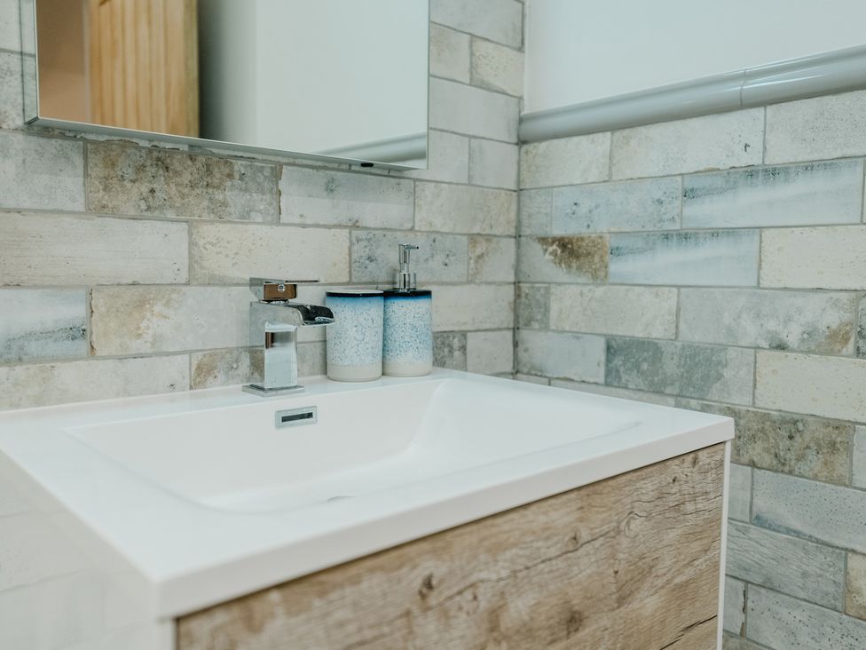 A sink with a faucet and toiletries at a bathroom