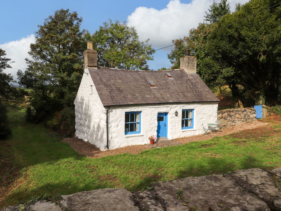 A house with a blue door and windows surrounded by greenery at Felin Bach Aberdaron