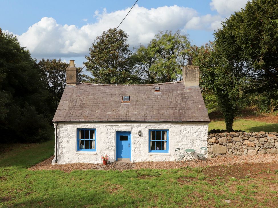 A cottage with blue windows and door surrounded by trees at Felin Bach Aberdaron