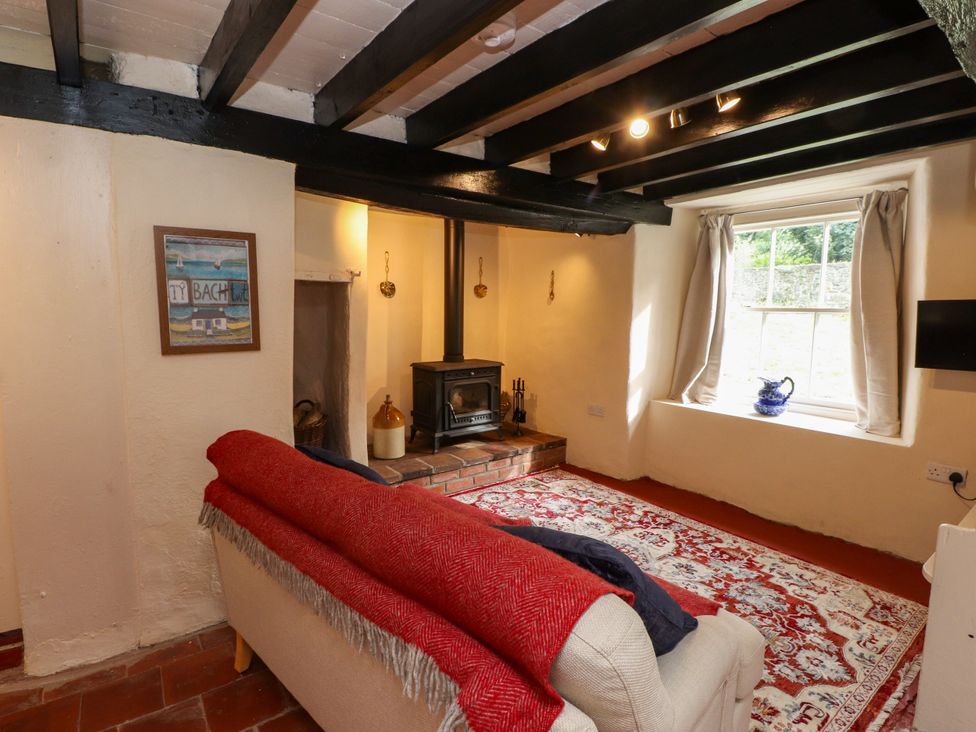A living room with a sofa and stove at Felin Bach in Aberdaron