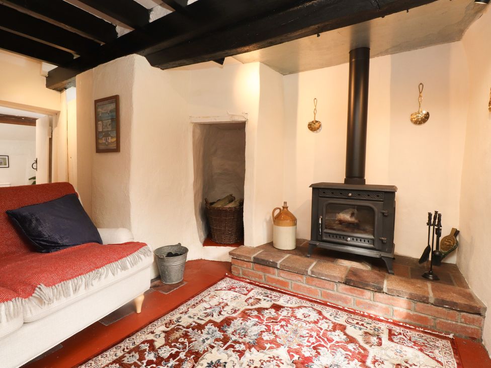 A snug with a stove and sofa at Felin Bach in Aberdaron