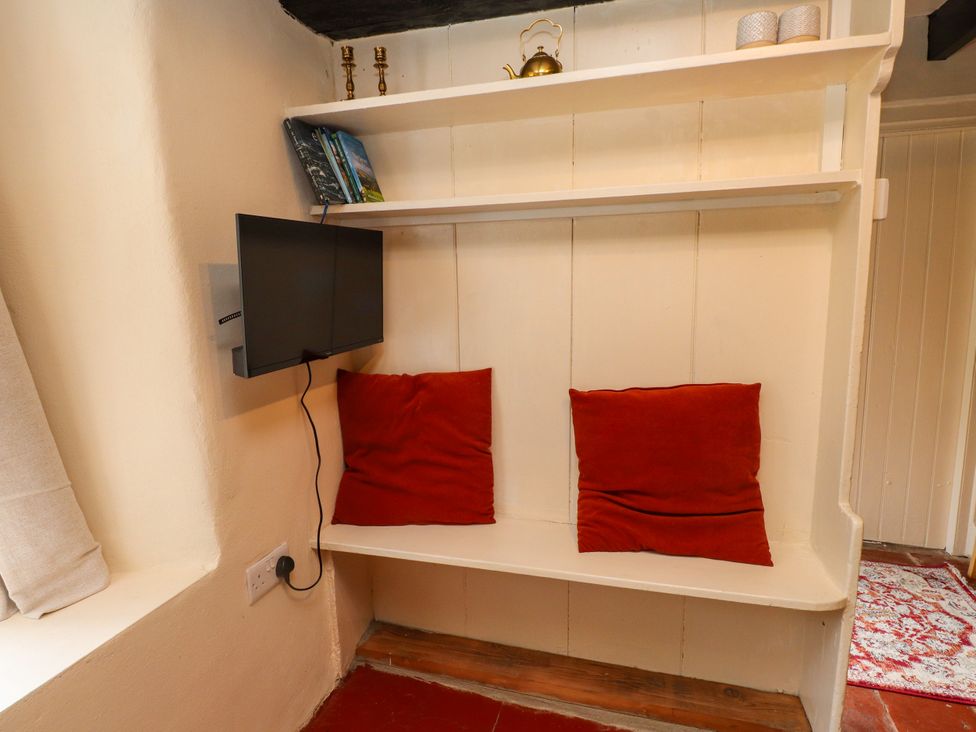 A snug area with a television and cushions at Felin Bach in Aberdaron