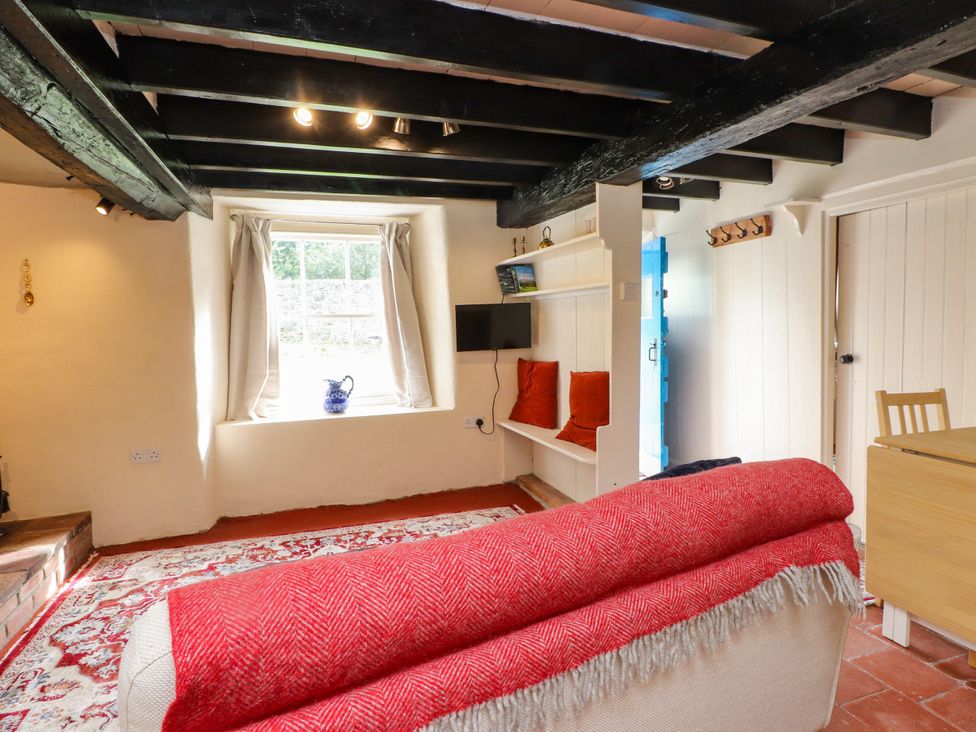 A living room with a couch, television, and table at Felin Bach, Aberdaron