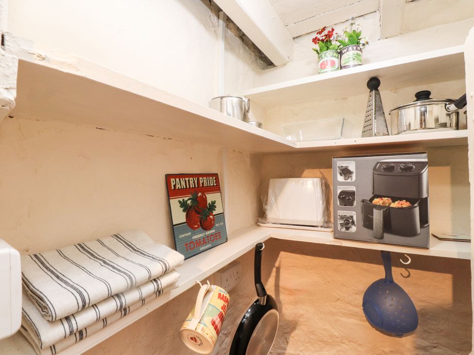 A pantry with shelves containing cooking utensils and appliances at Felin Bach Aberdaron
