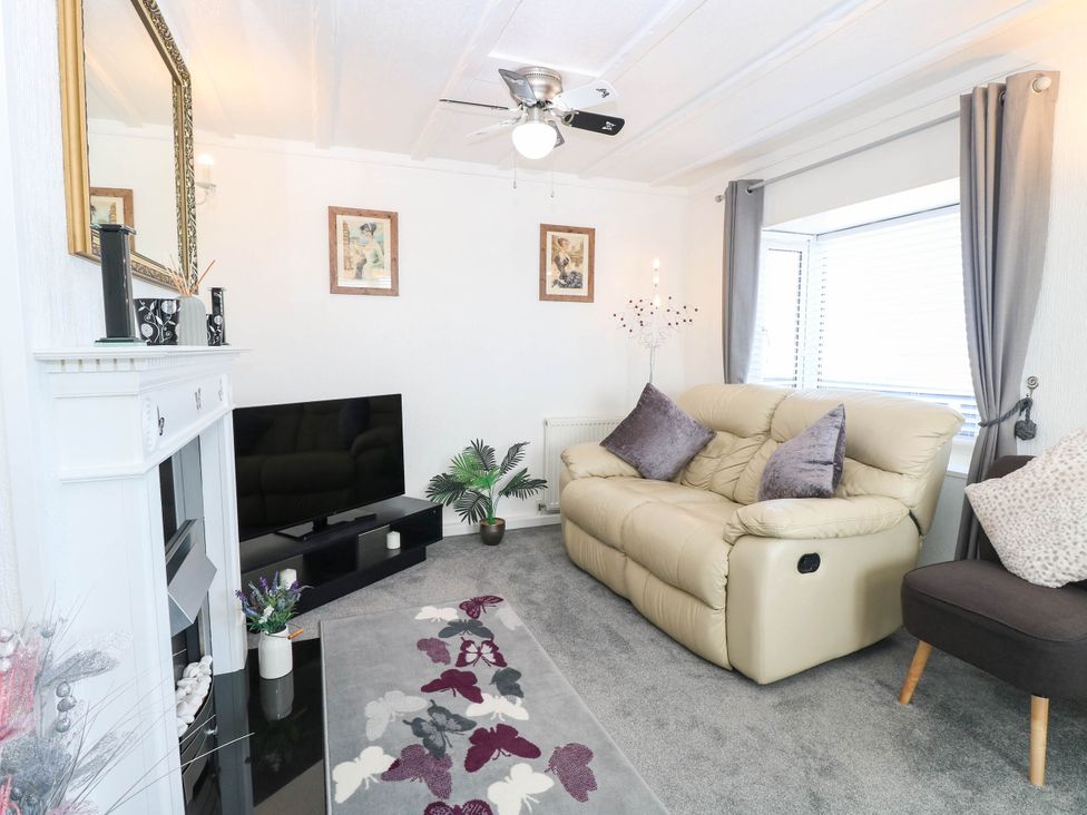 A living room with a sofa and television at Sea Mist in Trimingham