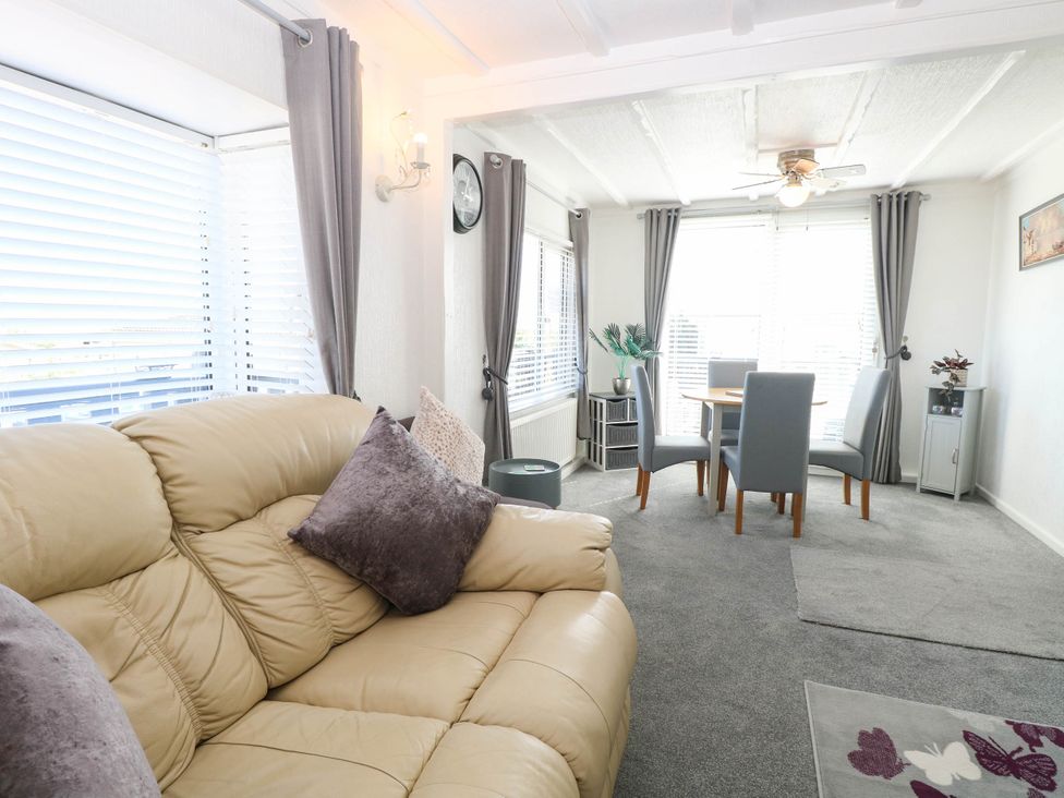 A living room with a sofa and dining area at Sea Mist in Trimingham