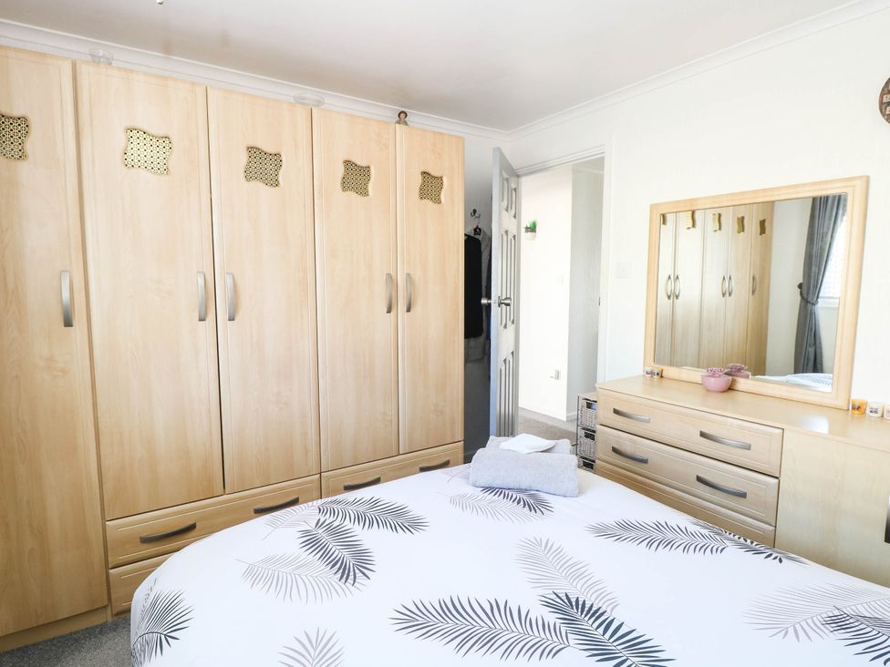 A bedroom with a wardrobe and a mirror at Sea Mist in Trimingham