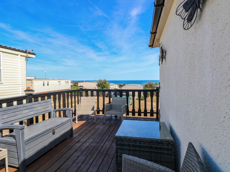 A deck with chairs and a table overlooking the ocean at Sea Mist in Trimingham