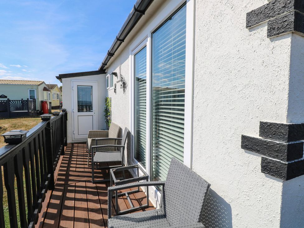 An outdoor deck with chairs and a door at Sea Mist in Trimingham