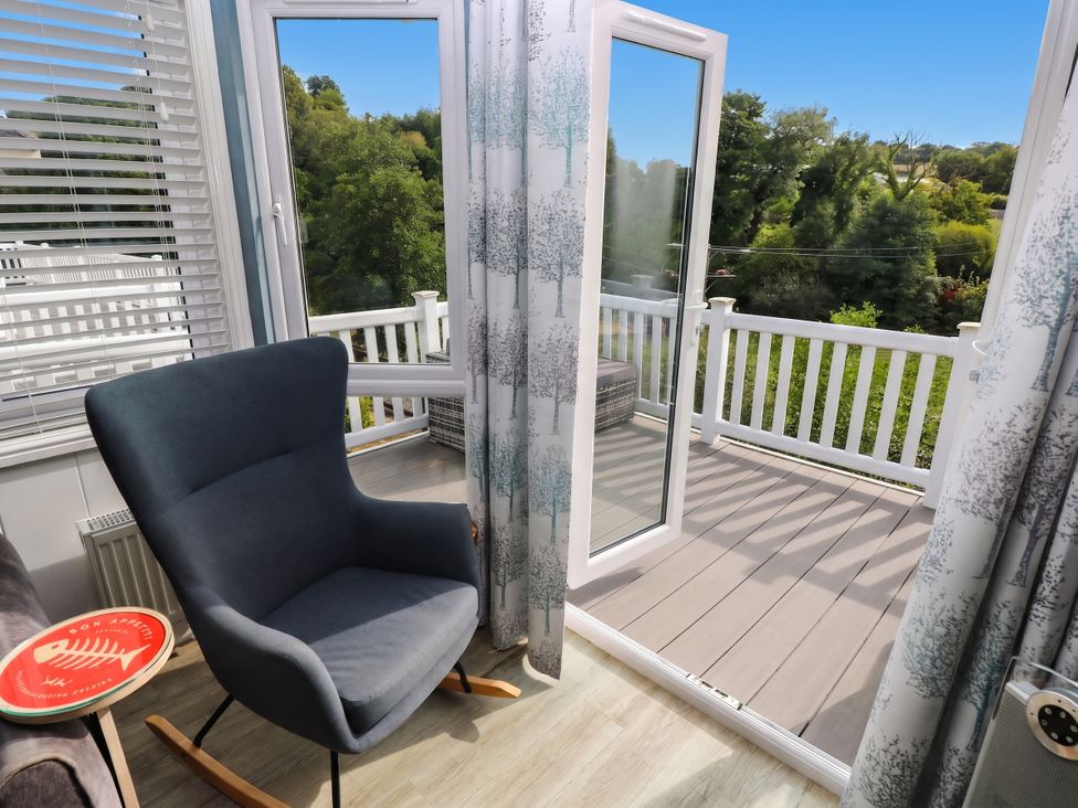 A conservatory with a rocking chair and open window at Pleasant Valley Holiday Lodge 70 in Stepaside