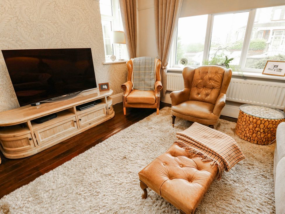 A living room with a television, two armchairs, and a coffee table at 11 Bryn Goleu Avenue North in Holyhead