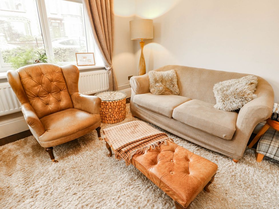 A living room with a sofa, armchair, and lamp at 11 Bryn Goleu Avenue North in Holyhead