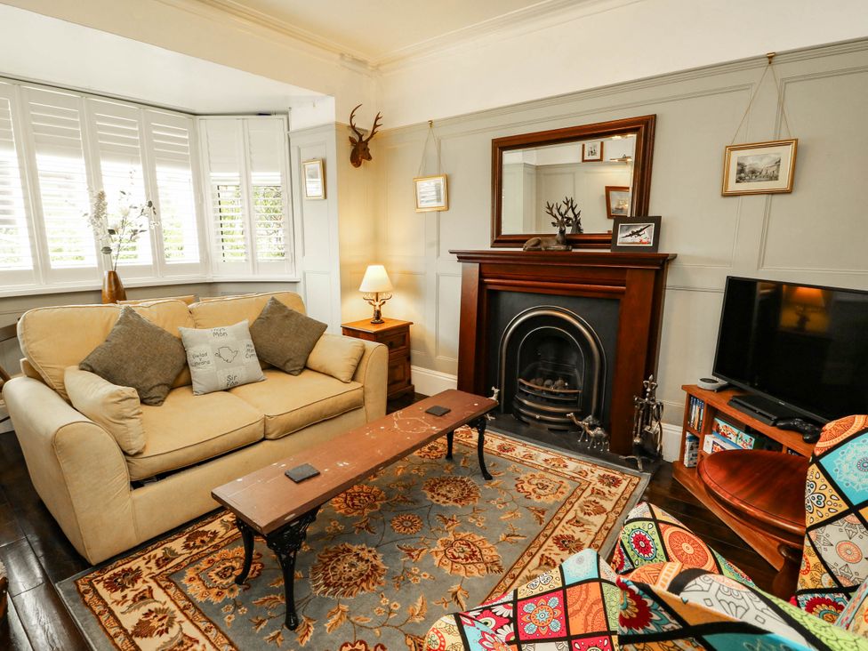 A living room with a sofa, fireplace and television at 11 Bryn Goleu Avenue North in Holyhead