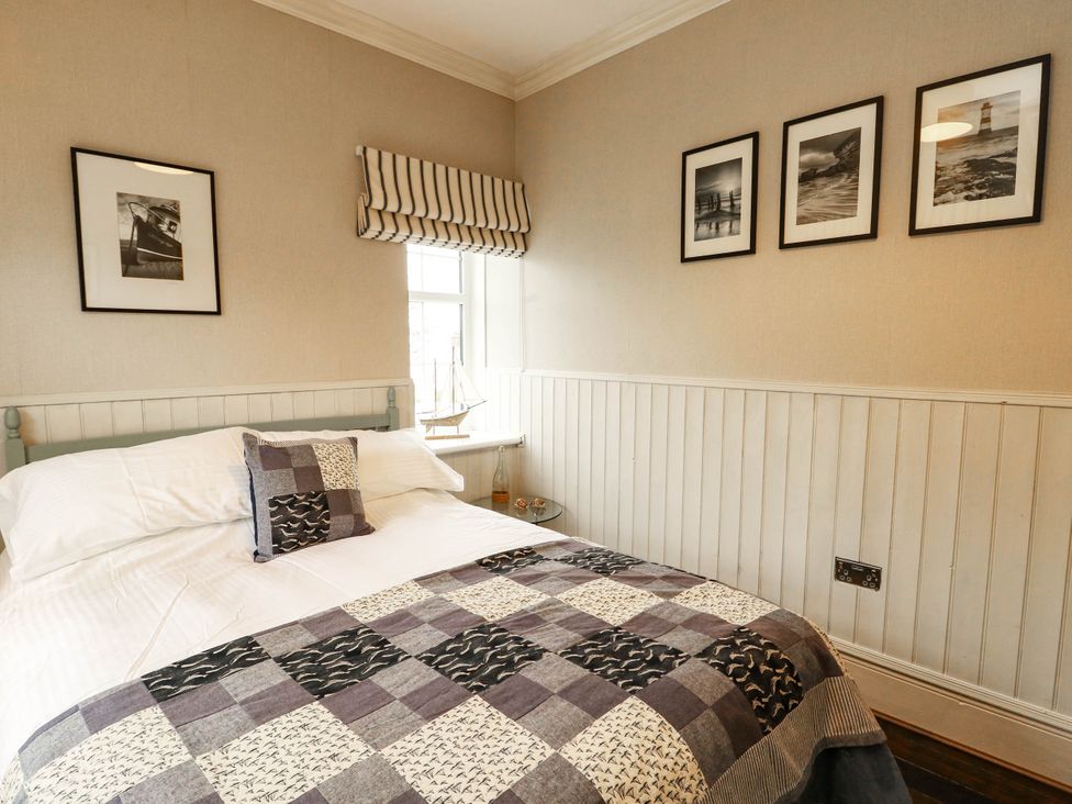 A bedroom with a bed and photographs on the wall at 11 Bryn Goleu Avenue North Holyhead