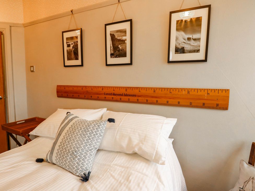 A bedroom with a bed and photographs on the wall at 11 Bryn Goleu Avenue North Holyhead