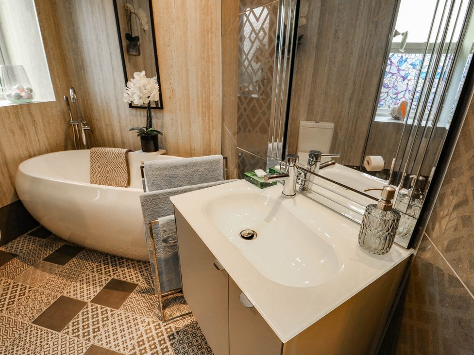 A bathroom with a bathtub and vanity sink at 11 Bryn Goleu Avenue North in Holyhead
