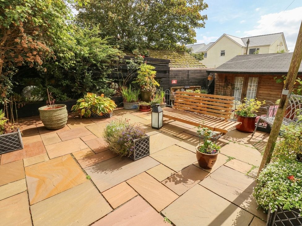 A garden with paving stones and a wooden bench at 11 Bryn Goleu Avenue North, Holyhead