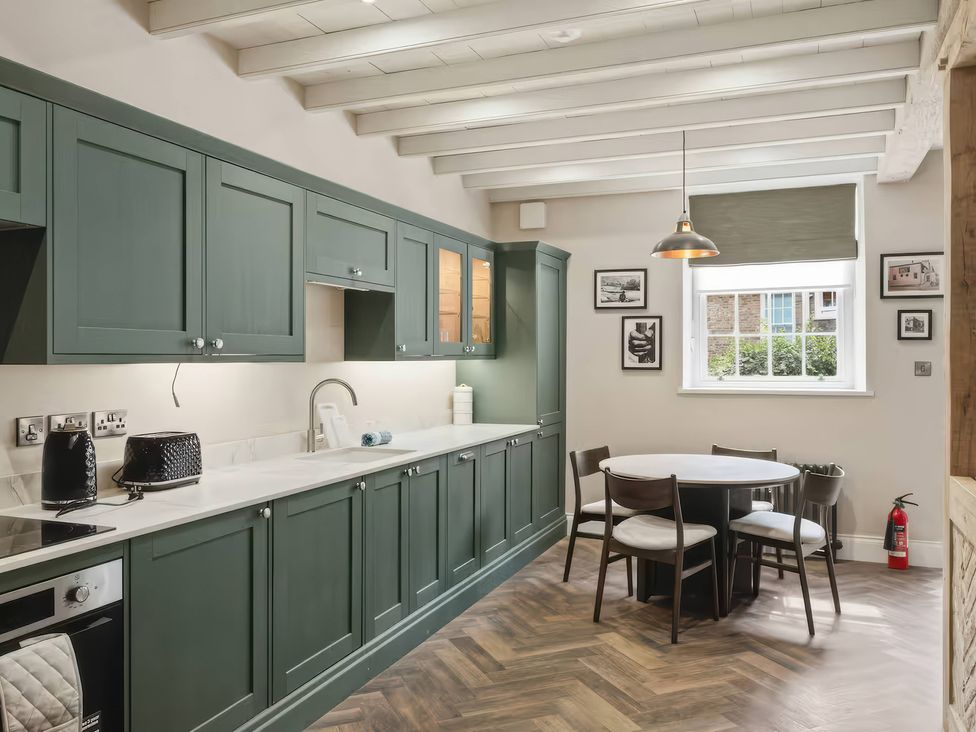 A kitchen with cabinets, counter, sink, dining table and chairs at Apt. 2 in York