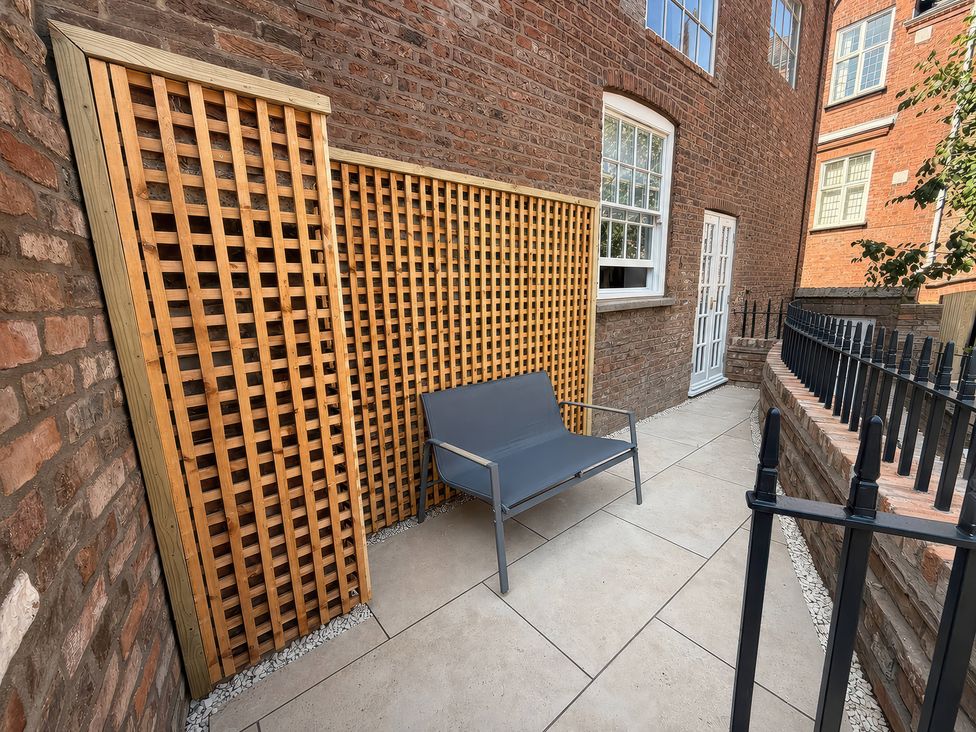 An outdoor seating area with a lattice panel and brick wall at Apt. 2 in York