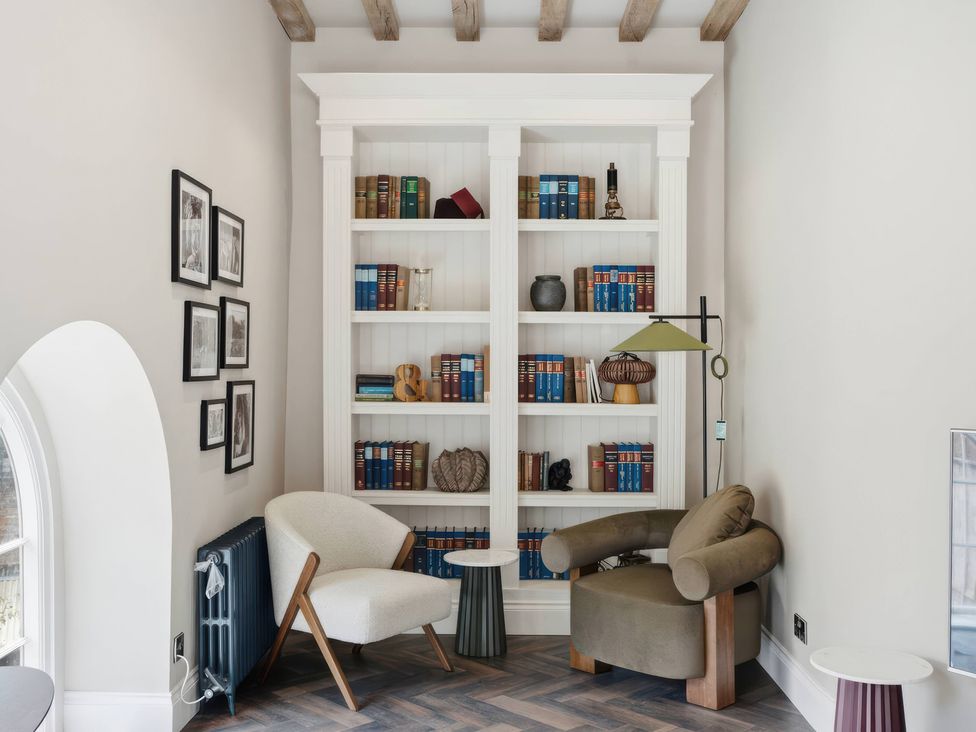 A sitting room with a bookshelf and a chair at Apt. 3 in York
