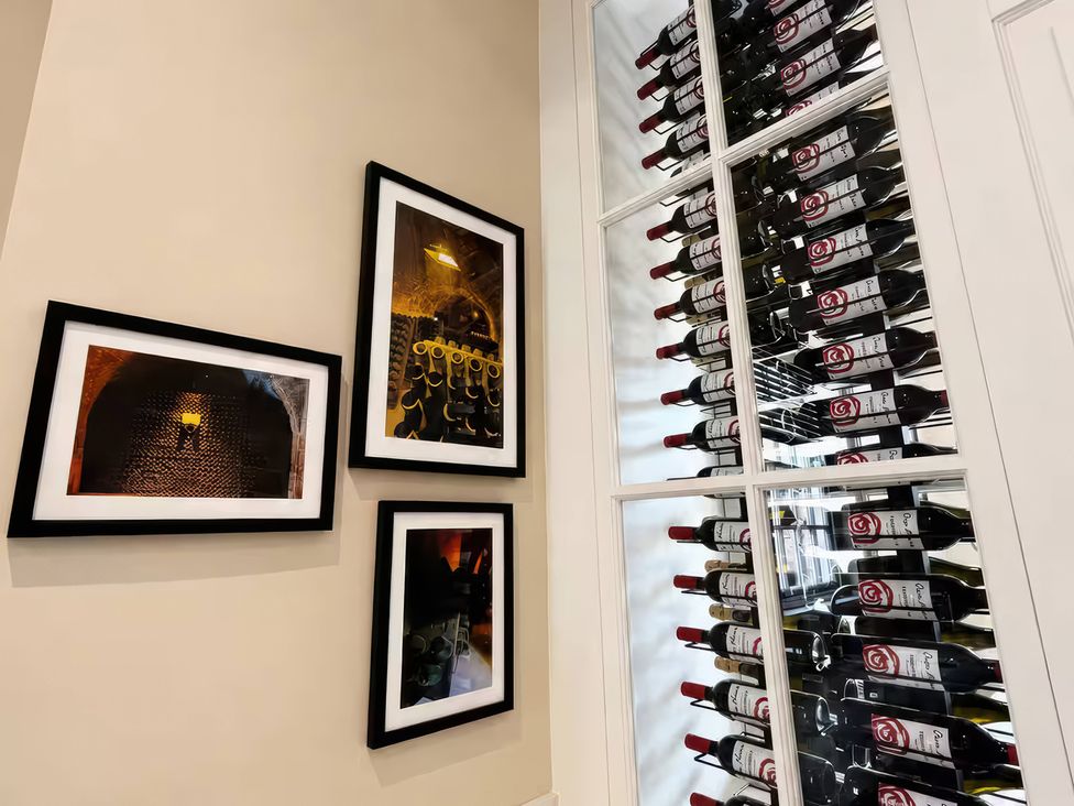 A wine cellar with wine bottles in a rack and framed photographs on the wall at Apt. 3 in York