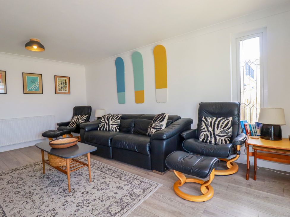 A living room with black leather seating and a coffee table at Mermaid Gaze in Newquay