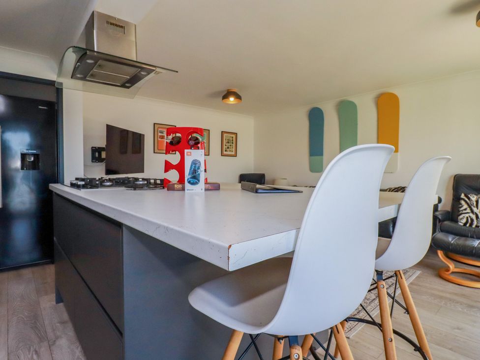 A kitchen with a white island and black appliances at Mermaid Gaze in Newquay