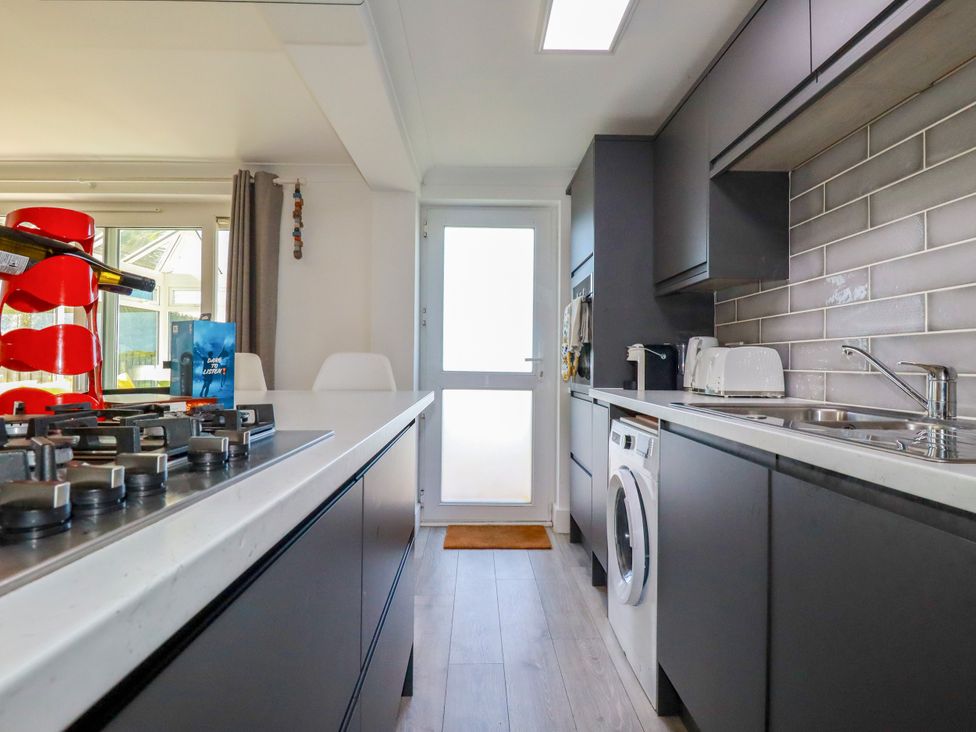 A kitchen with a sink and washing machine at Mermaid Gaze in Newquay