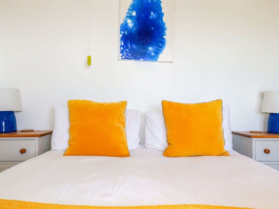 A bedroom with a bed and yellow pillows at Mermaid Gaze in Newquay