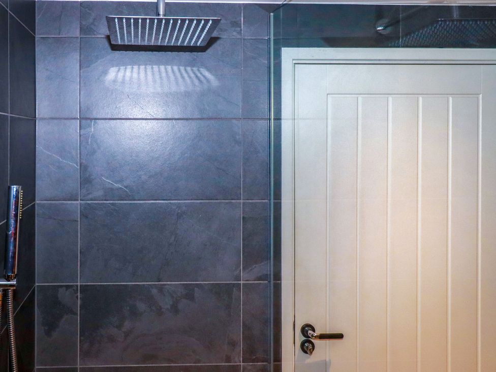 A bathroom with a showerhead and a door at Mermaid Gaze in Newquay