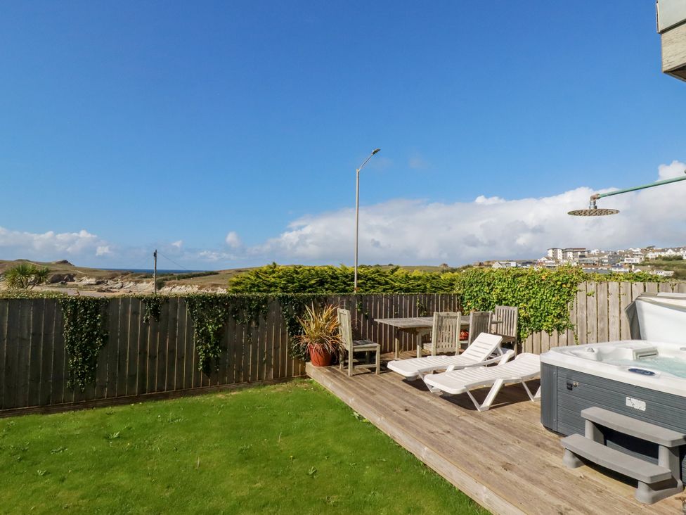 A garden with sun loungers and a hot tub at Mermaid Gaze in Newquay