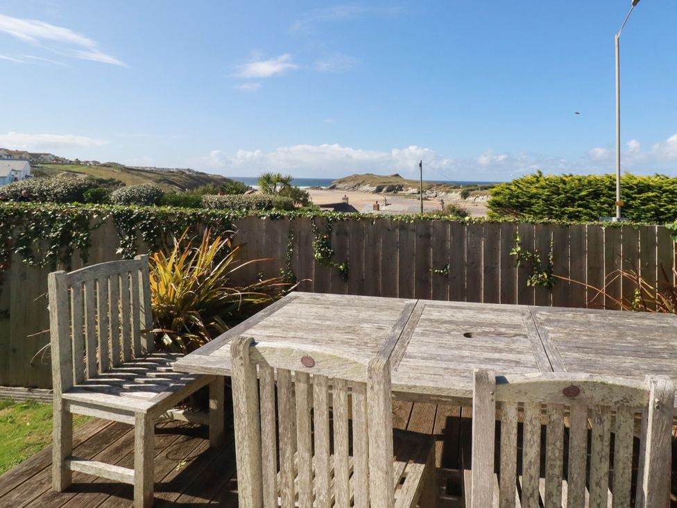 An outdoor seating area with a wooden table and chairs overlooking the sea at Mermaid Gaze Newquay