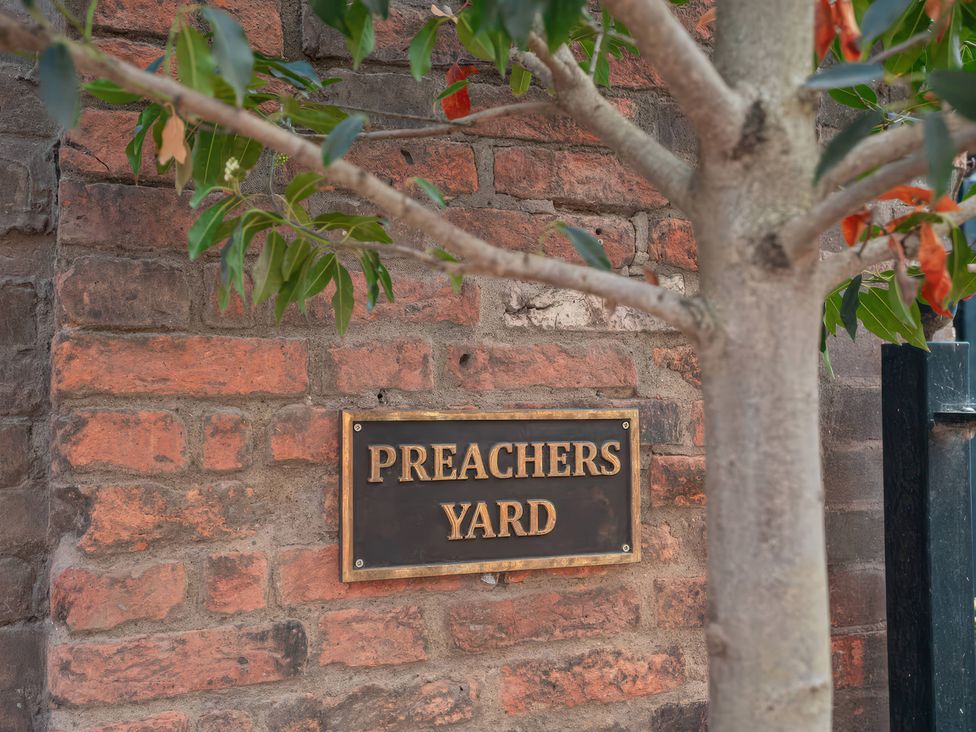 A sign that reads Preachers Yard next to a tree