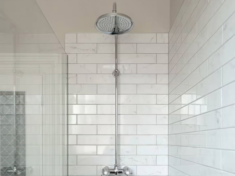 A shower with a chrome shower head and marble tile at Apt.4 in York