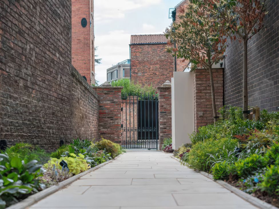 A pathway leading to a gate with plants and trees at Apt.4, York