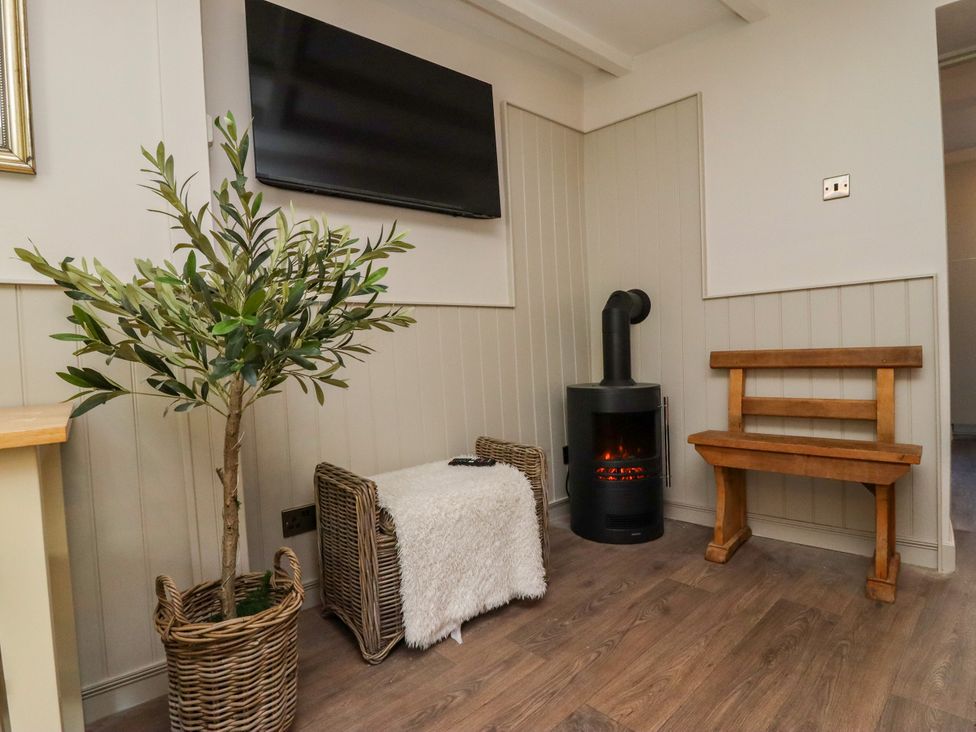 A living room with a television, plant, and stove at Blue Cottage in Malton