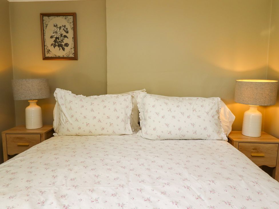 A bedroom with a bed and nightstands at Blue Cottage in Malton
